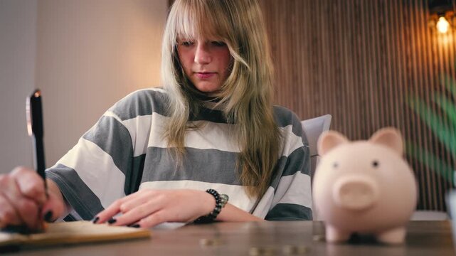 Teenager planning personal budget, writing expenses in notebook, saving money, financial literacy and student finance concept at home.