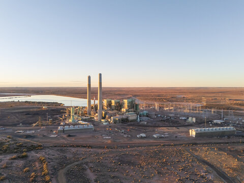 Joseph City, United States - 05 April 2026: Aerial view of Cholla Power Plant with its tall smokestacks and industrial structures set against the arid desert landscape and cooling ponds at sunset.