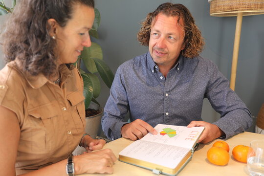 Business Meeting Discussion: a man and a woman speaking together and looking at an open book
