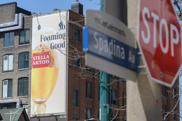 Fototapeta premium wall mounted advertising banner on the exterior brick building for Stella Artois, a beer, incl defocused traffic signs, Toronto Spadina Av