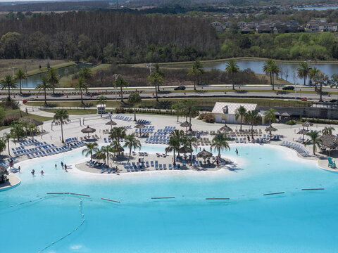 Wesley Chapel, United States - 02 March 2026: Aerial view of Epperson Lagoon featuring turquoise water, white sand beaches, and palm trees with people relaxing on lounge chairs.