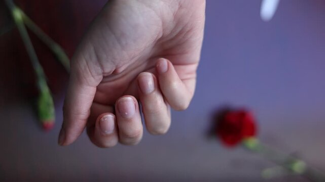 Close-up of a female hand held in front of the viewer, showing natural nails that need care and maintenance. 