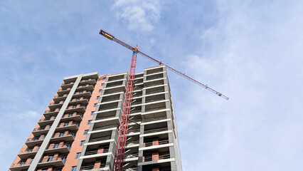 Tower crane standing tall next to a multi story residential building frame, showing the progress of modern building construction and the dynamic urban landscape © Newleks