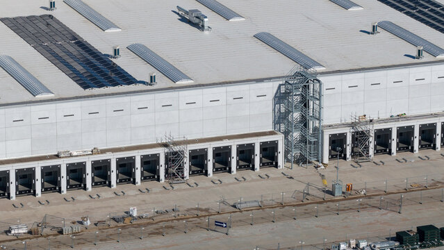 Lelystad, Netherlands - 21 April 2026: Aerial view of the JYSK DCL construction site featuring a large warehouse with loading docks and solar panels on the roof.