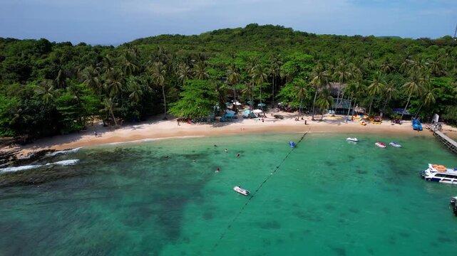Stunning aerial footage of Hon Vong Island Beach with turquoise blue water and sandy beach with tourist boats anchored and people swimming on a hot summer day in Phu Quoc South Vietnam