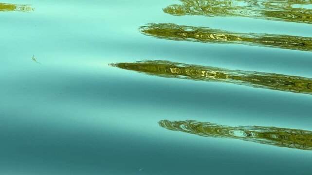Reflections of light on water from soft waves in flowing water with blue, turquoise and green colours. Backgrounds.  