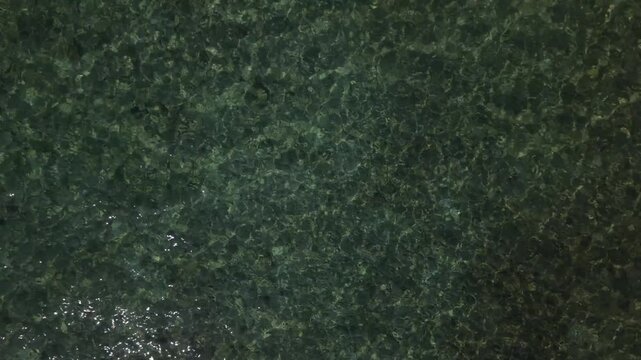Still shot of rippling water revealing submerged rocks