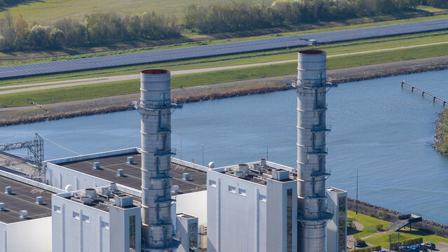 Lelystad, Netherlands - 21 April 2026: Aerial view of the Maxima plant power station and offshore wind turbines along the coast under a clear blue sky.