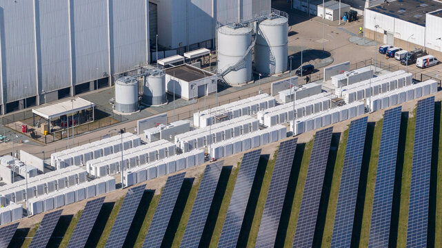 Lelystad, Netherlands - 21 April 2026: Aerial view of the Maxima plant power station and offshore wind turbines along the coast under a clear blue sky.
