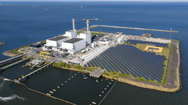 Lelystad, Netherlands - 21 April 2026: Aerial view of the Maxima plant power station and offshore wind turbines along the coast under a clear blue sky.