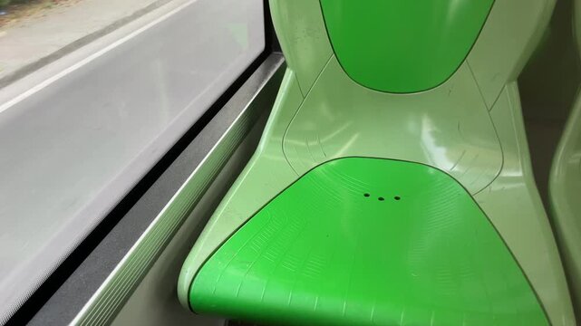 Modern Train Interior: A close-up view of the interior of a train, featuring sleek, modern seating in vibrant green, with the window visible, offering a glimpse of the outside world.