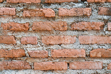 Fototapeta premium Close-up of an old weathered red brick wall with rough grey mortar, featuring a rustic and vintage texture.
