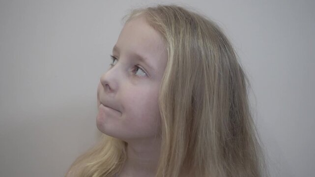 Child opening his mouth wide on a light background, Full-face portrait of a girl, Open mouth and tense look convey a state of stress, facial expressions of a child
