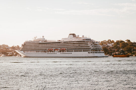 Large white cruise ship moving steadily across calm harbour water