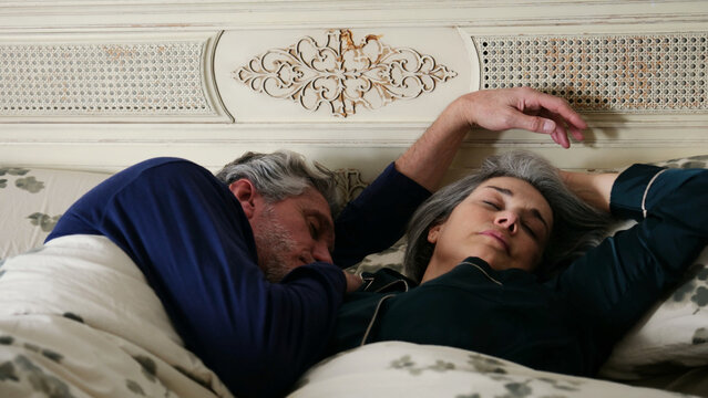 Senior couple sleeping peacefully together in a comfortable bed, finding rest and relaxation