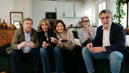 Fototapeta premium Senior people sitting on a sofa playing video games and having fun