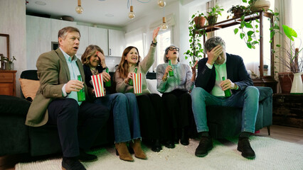Fototapeta premium Group of friends watching a game on TV, cheering and feeling disappointed