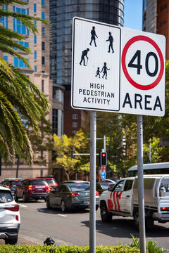Speed limit and traffic caution sign with city and cars in background