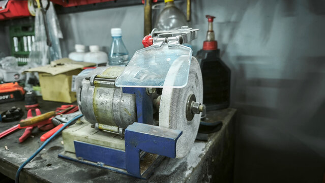 bench grinder machine with a protective shield, used for polishing and sharpening tools. Perfect for industrial or workshop settings.