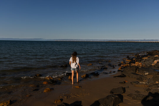 girl walking on the sea shore in the afternoon light