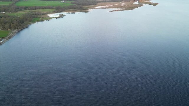 Aerial View of Calm Water of Massive Lake at Balmaha Valley Village Near Glasgow Landscape During Sunset. Village is a popular tourist destination for picnickers and day trippers from Glasgow