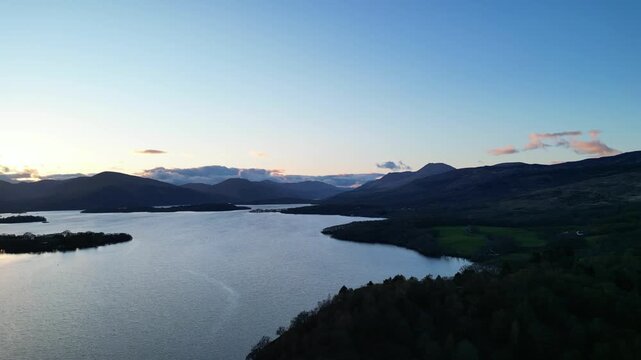Aerial View of Calm Water of Massive Lake at Balmaha Valley Village Near Glasgow Landscape During Sunset. Village is a popular tourist destination for picnickers and day trippers from Glasgow