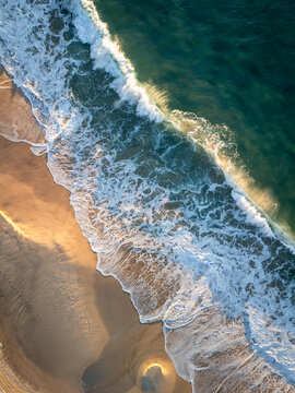 Coogee, Australia - 12 April 2026: Aerial view of Coogee Beach with turquoise waves crashing onto the golden sand during sunrise.