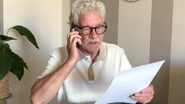 Elderly man with gray hair and glasses communicates on his smartphone, attentively reading a document. He appears focused on a business or personal discussion, highlighting modern communication and re