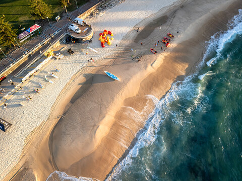 Coogee, Australia - 12 April 2026: Aerial view of Coogee Beach featuring golden sand, surf rescue boats, and people near the promenade during golden hour.