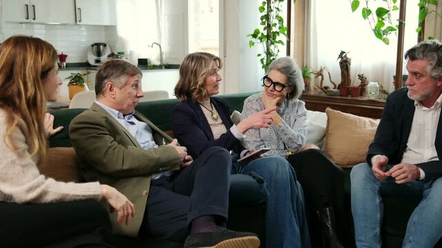 Group of senior friends sitting on a sofa and happily chatting in a living room