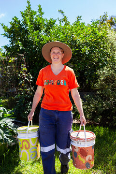 Australian woman in backyard garden carrying buckets for food scraps to compost
