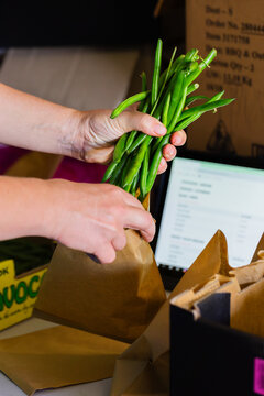 Woman packing organic beans into brown bag at local food distribution hub