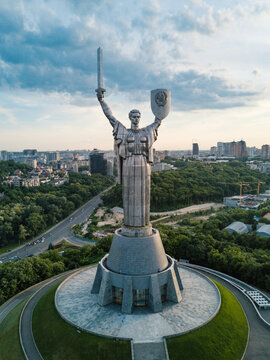 Kyiv, Ukraine - 27 May 2019: Aerial view of the Motherland Monument statue with its sword and shield raised over the lush green hills and city skyline.