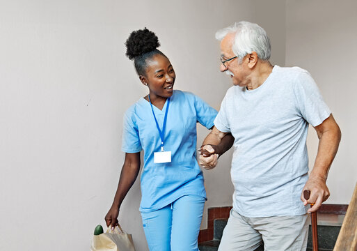 Doctor or nurse caregiver helping disabled senior man walking down the stairs at home or nursing home