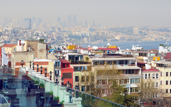 Panoramic aerial view of Istanbul city buildings and Bosphorus strait. Urban landscape features colorful houses, rooftops and modern skyscrapers of Istanbul under hazy daylight sky in Turkey