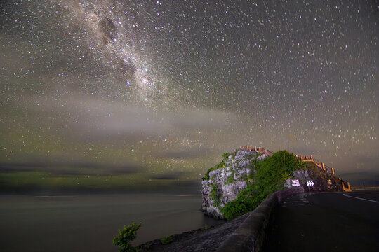 Long exposure night landscape photograph capturing the Milky Way stretching across the sky above the dramatic coastal cliffs of Maconde Viewpoint. 
