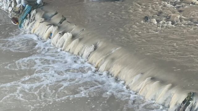 Small waterfall flowing over concrete dam in river