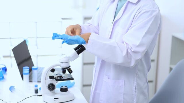 Teen girl in white coat wearing gloves before research task in a modern lab. Science, laboratory, scientist, experiment, and research express lab readiness and scientific process, curiosity.