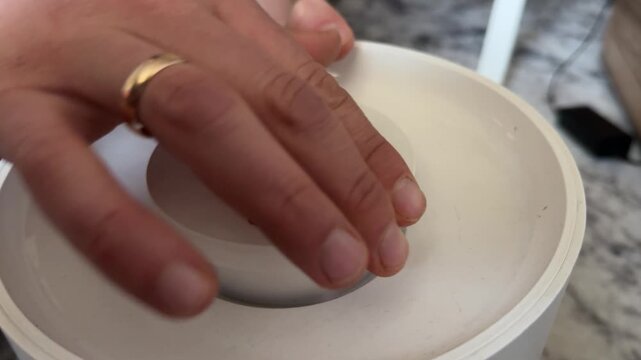 Hand placing lid on round kitchen appliance container