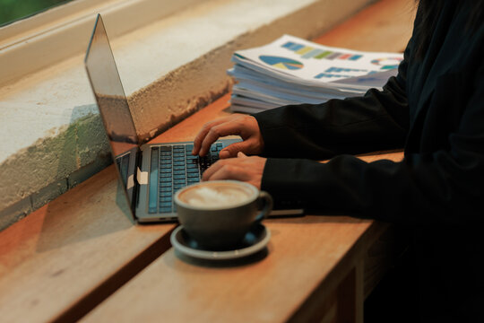 Young professional woman in an office, focused on detailed data entry while examining physical files, highlighting self-discipline and career success.