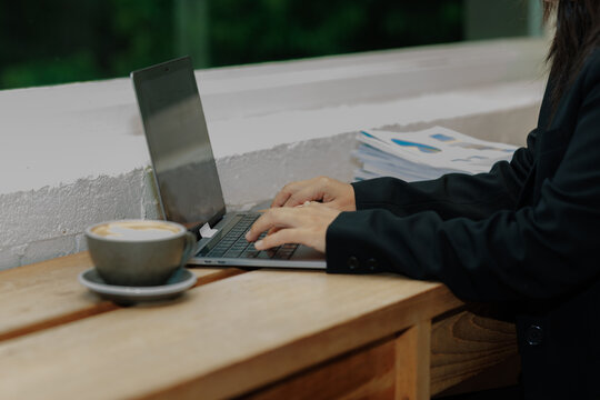 Young professional woman in an office, focused on detailed data entry while examining physical files, highlighting self-discipline and career success.