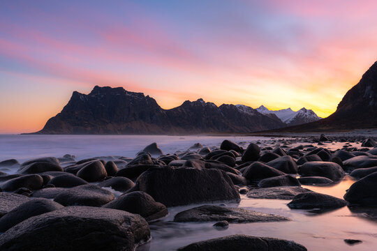 Sunset over rocky beach with mountains in the background