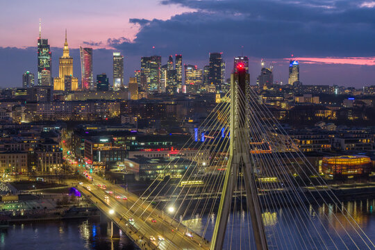 Warsaw, Poland - 20 March 2026: Aerial view of the Swietokrzyski Bridge and the illuminated city skyline with skyscrapers under a twilight sky.