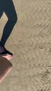 Piedi con smalto rosa sulla sabbia
