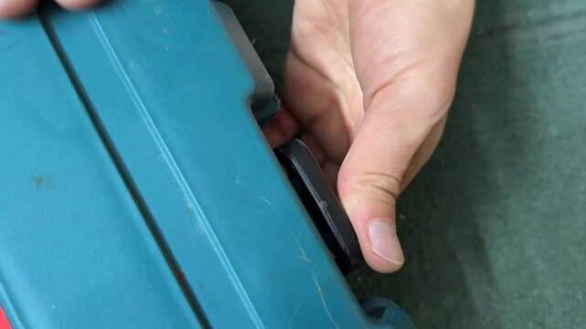 Hands adjusting latch on plastic equipment case, closing storage box mechanism, tool container handling