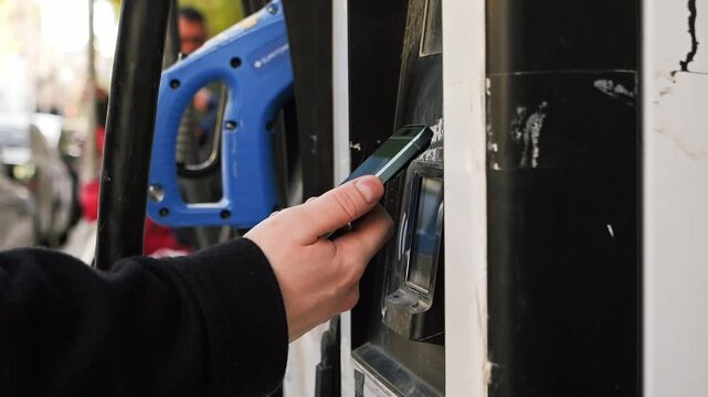 Man using contactless payment by mobile phone with QR code at car filling station, payment for gasoline or electric car charge. 