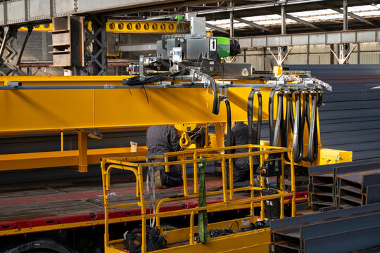 Workers assembling overhead bridge crane in industrial steel warehouse