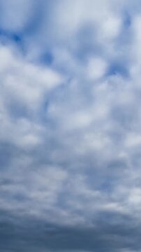 Dramatic cloudscape covering the horizon. Grey heavy clouds evanesce gradually in the sky. Low angle view. Vertical video