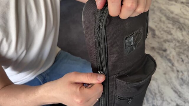 Two hands are shown unzipping a guitar case