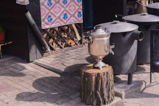 traditional samovar on a wooden stump in a rustic setting. evoking traditional tea culture. samovar is surrounded by rustic decor and a wooden floor, conveying a sense of warmth and tradition.